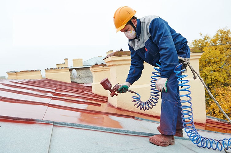 A roof painter spraying a roof